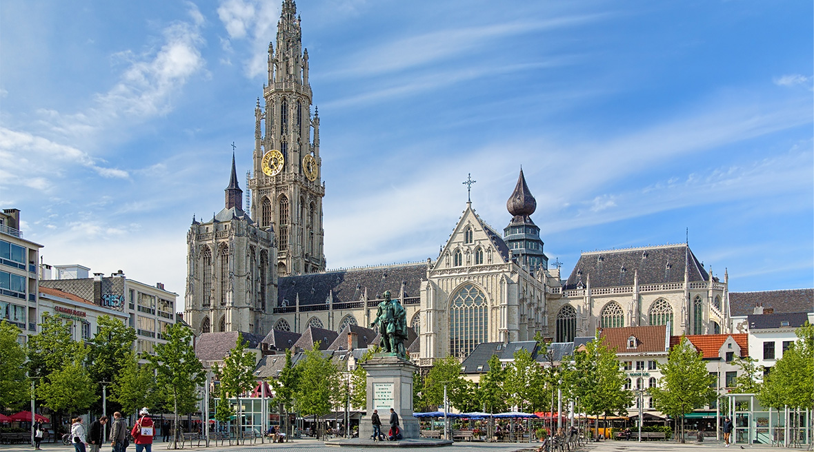 Gothic cathedral with a tall spire, square and statue in front